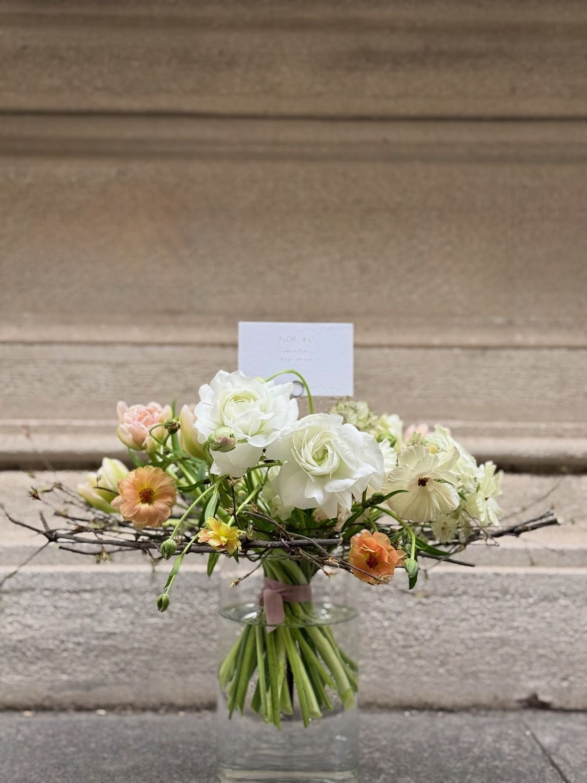 Bouquet bianco e pesca in vaso di vetro su gradino in pietra