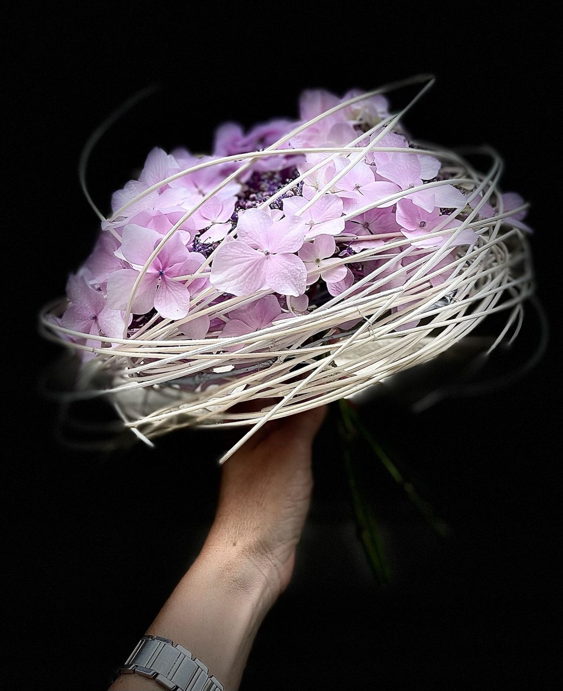 Bouquet di ortensie lilla avvolto da fili bianchi, su fondo nero
