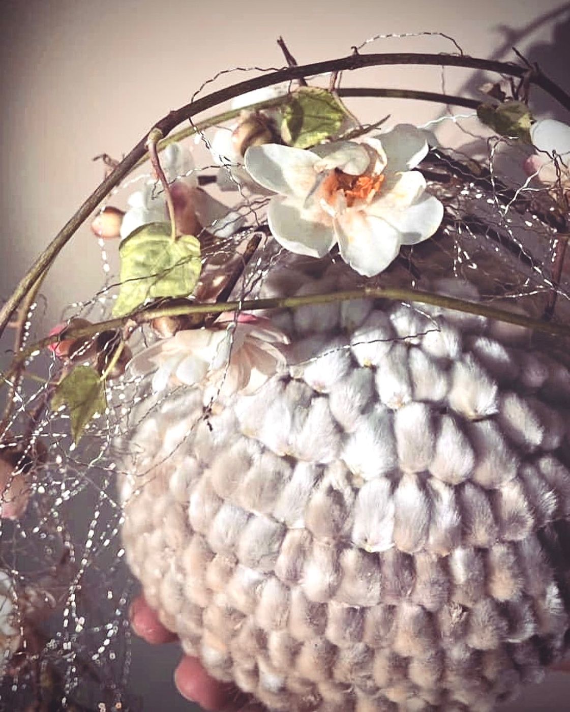 Sfera di cotone con orchidee e fili di perle, tenuta in mano